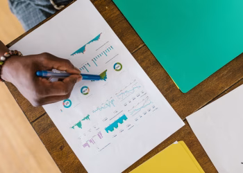 Overhead view of a person analyzing business charts and graphs on paper.