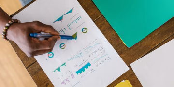 Overhead view of a person analyzing business charts and graphs on paper.