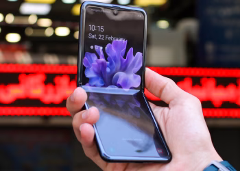 Close-up of a modern flip smartphone held in hand, showcasing innovative technology outdoors in a bustling city.