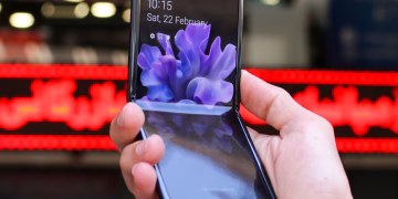 Close-up of a modern flip smartphone held in hand, showcasing innovative technology outdoors in a bustling city.