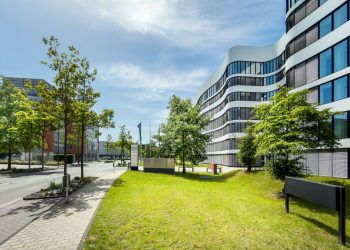 Contemporary business office building with curved architecture and trees in an urban setting.