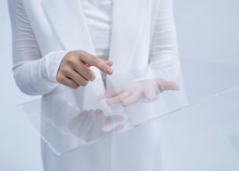 Person in white interacting with a clear glass interface, suggesting technological innovation.