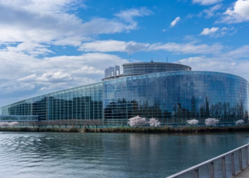 Modern architecture of the European Parliament building in Strasbourg with a reflective glass facade and river view.