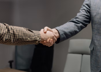 Close-up of two professionals shaking hands in an office, symbolizing successful business dealings.
