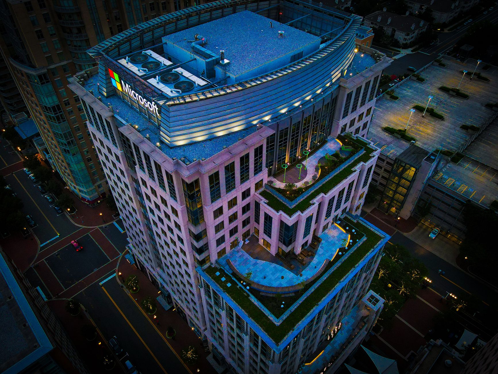 High-angle nighttime view of a modern urban skyscraper with rooftop garden.