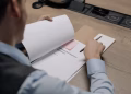 Business professional at the desk examining a software development agreement document.