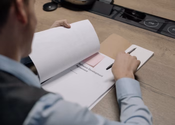 Business professional at the desk examining a software development agreement document.