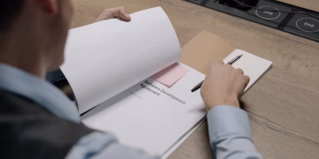 Business professional at the desk examining a software development agreement document.