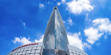View of Lotte World Tower in Seoul under a bright blue sky, showcasing modern architecture.
