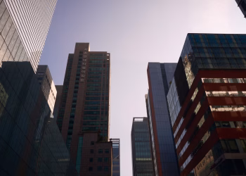 Modern skyscrapers with glass facades reflecting daylight in a bustling cityscape.