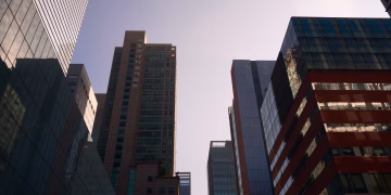 Modern skyscrapers with glass facades reflecting daylight in a bustling cityscape.