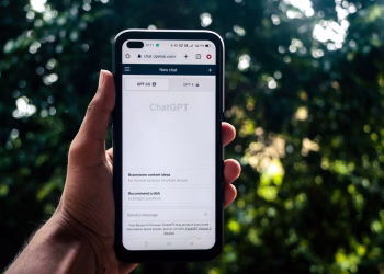 A person uses ChatGPT on a smartphone outdoors, showcasing technology in daily life.