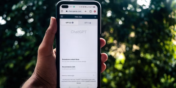 A person uses ChatGPT on a smartphone outdoors, showcasing technology in daily life.