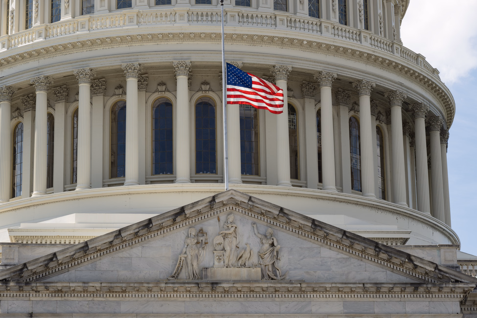 Close-up of the Capitol building in Washington DC with the US flag waving in front.