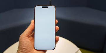 Closeup of a hand holding a smartphone with a blank screen, perfect for app mockups and presentations.