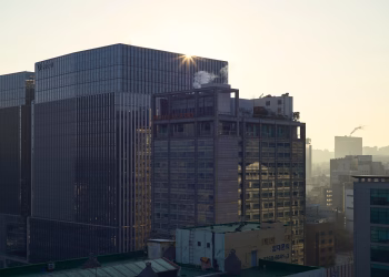Sunrise illuminates city skyline with modern skyscrapers, adding a warm glow.