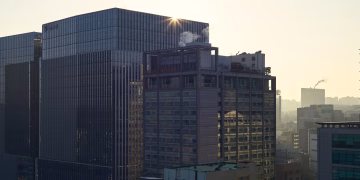 Sunrise illuminates city skyline with modern skyscrapers, adding a warm glow.