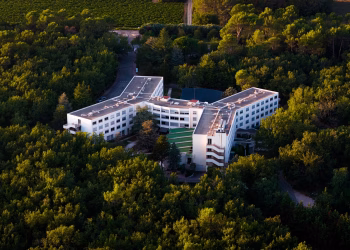 Aerial shot of a modern hotel nestled in a lush green forest.