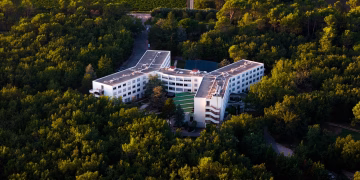 Aerial shot of a modern hotel nestled in a lush green forest.
