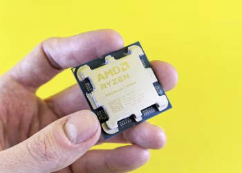 Detailed shot of AMD Ryzen 7 9700X processor held against bright yellow background.