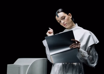 A female scientist with futuristic attire reviews notes in an advanced lab setting.