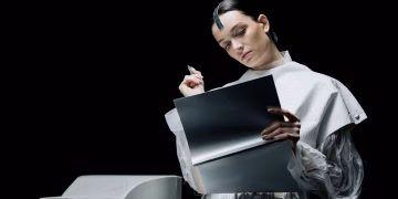 A female scientist with futuristic attire reviews notes in an advanced lab setting.