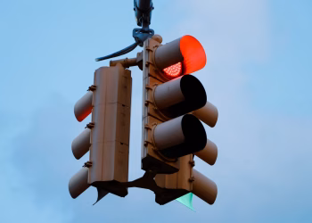 Close-up of a red traffic light signaling stop against a clear blue sky.