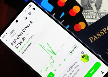 Smartphone displaying stock market app next to U.S. dollar and passport, representing global finance.