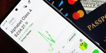 Smartphone displaying stock market app next to U.S. dollar and passport, representing global finance.