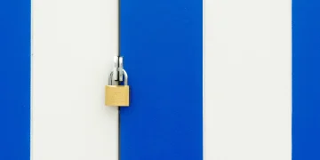 Padlock securing a blue and white striped door, symbolizing safety.