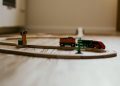 A close-up view of a colorful wooden toy train set on a wooden floor indoors.