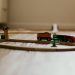 A close-up view of a colorful wooden toy train set on a wooden floor indoors.