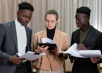 A multi-ethnic group of professionals reviewing documents together in a corporate setting.
