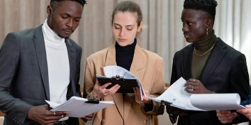 A multi-ethnic group of professionals reviewing documents together in a corporate setting.