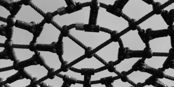 Black and white close-up of an intricate playground climb structure showcasing geometric patterns.