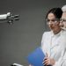 Two scientists wearing lab coats and goggles analyzing a robotic arm in a laboratory setting.