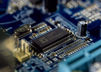 Detailed shot of a microprocessor on a blue motherboard showcasing electronic components.