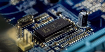 Detailed shot of a microprocessor on a blue motherboard showcasing electronic components.