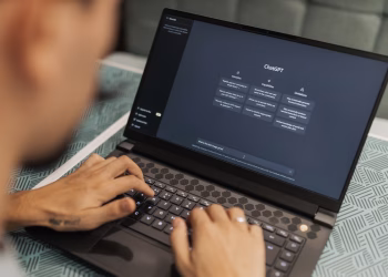 Close-up of a person typing on a laptop displaying the ChatGPT interface, emphasizing modern technology use.