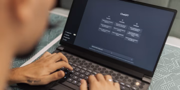 Close-up of a person typing on a laptop displaying the ChatGPT interface, emphasizing modern technology use.