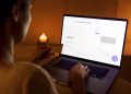 A woman makes a secure online payment using a laptop and credit card in a cozy setting.