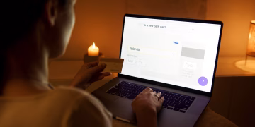 A woman makes a secure online payment using a laptop and credit card in a cozy setting.