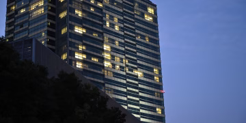 A tall building with lit windows against a dusky blue sky, conveying urban nightlife.