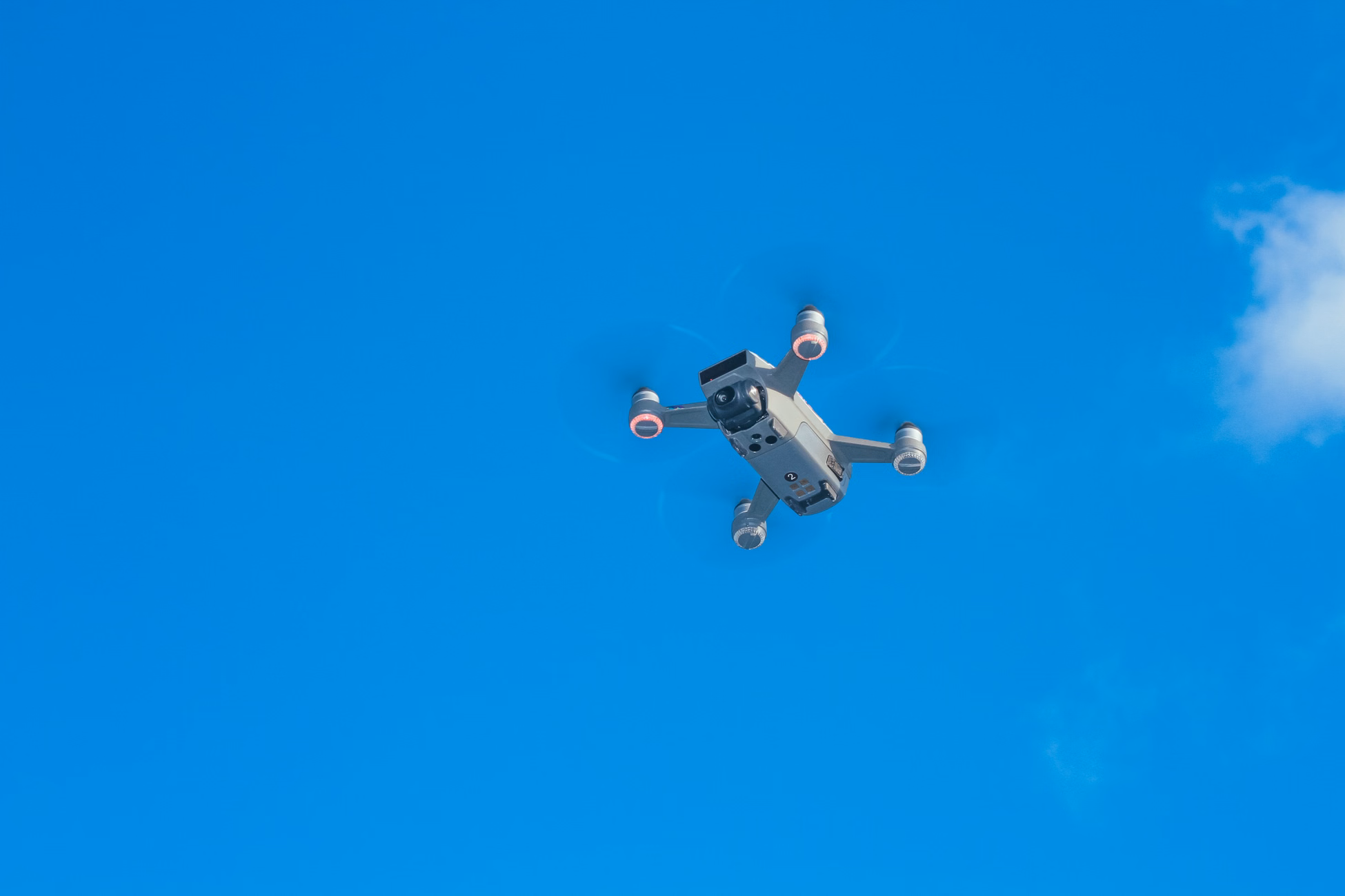 From below of quadcopter with small propellers and motors flying in vibrant blue sky