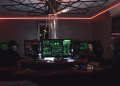 Team of hackers with Guy Fawkes masks coding in a dark room with computers.