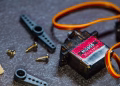 Detailed view of an MG90S micro servo motor with screws and components for robotics applications.
