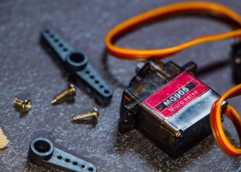 Detailed view of an MG90S micro servo motor with screws and components for robotics applications.