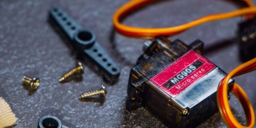 Detailed view of an MG90S micro servo motor with screws and components for robotics applications.