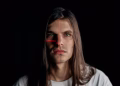 Studio portrait of a man with long hair featuring a facial recognition laser grid.