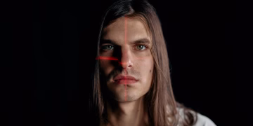 Studio portrait of a man with long hair featuring a facial recognition laser grid.